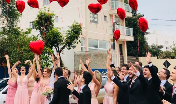 Persone che festeggiano e lanciano palloncini rossi a forma di cuore